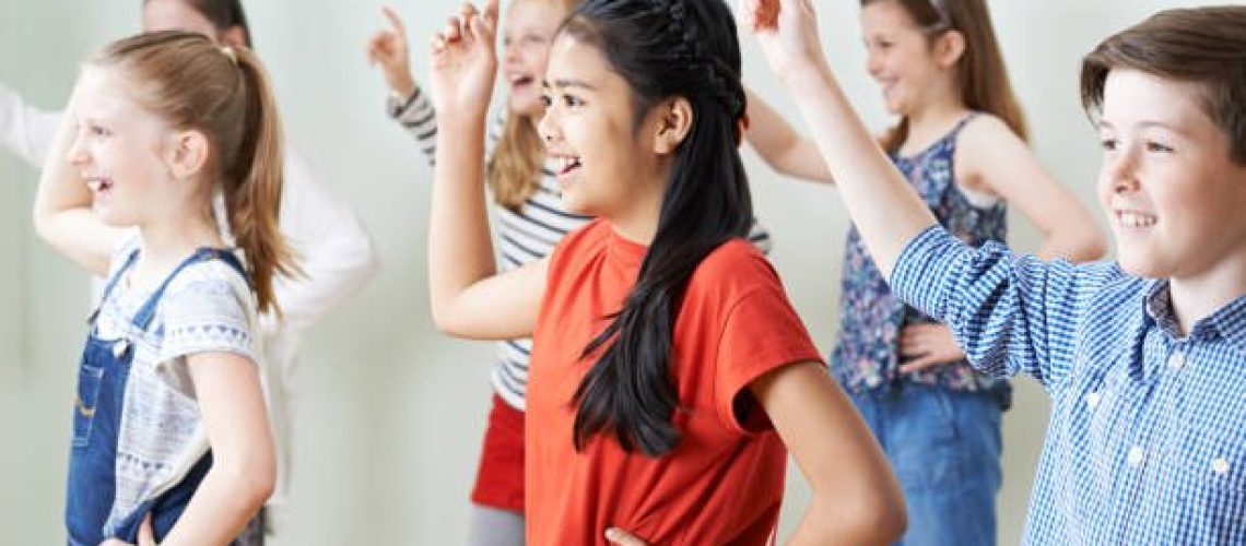 Group Of Children Dancing In Drama Class Together